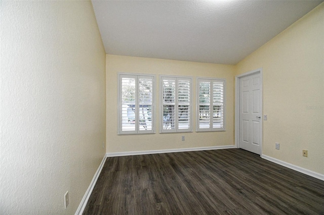 spare room with dark wood-type flooring and vaulted ceiling