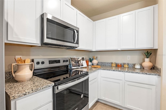 kitchen with light stone countertops, light tile patterned floors, stainless steel appliances, and white cabinets