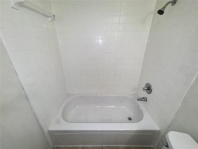 bathroom featuring tiled shower / bath and toilet