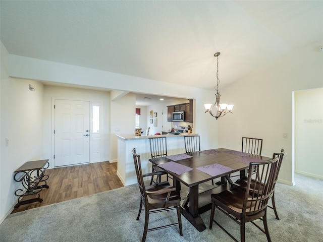 carpeted dining space with vaulted ceiling and a chandelier