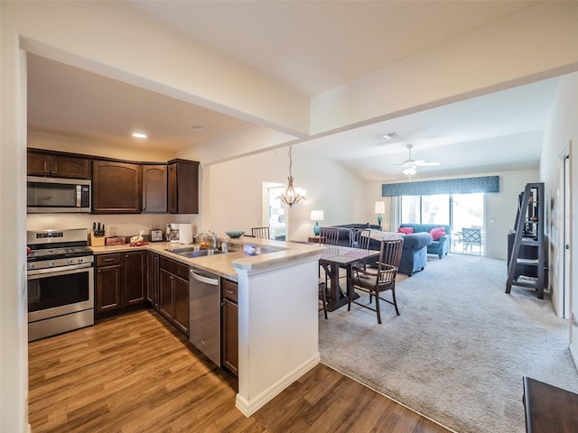 kitchen featuring appliances with stainless steel finishes, sink, hanging light fixtures, dark brown cabinetry, and kitchen peninsula