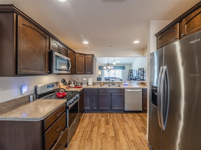 kitchen with dark brown cabinetry, sink, an inviting chandelier, light hardwood / wood-style flooring, and stainless steel appliances