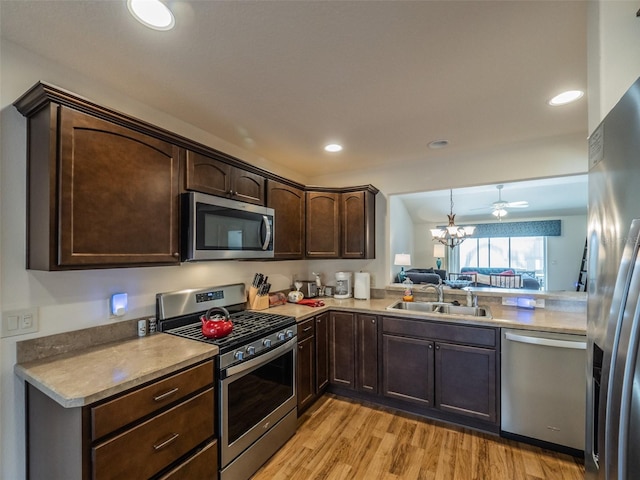 kitchen with sink, dark brown cabinets, light hardwood / wood-style flooring, appliances with stainless steel finishes, and ceiling fan with notable chandelier