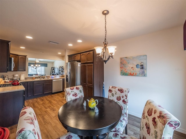 dining room featuring wood-type flooring, sink, and a chandelier