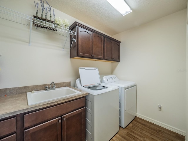 washroom featuring sink, dark wood-type flooring, cabinets, a textured ceiling, and washing machine and clothes dryer