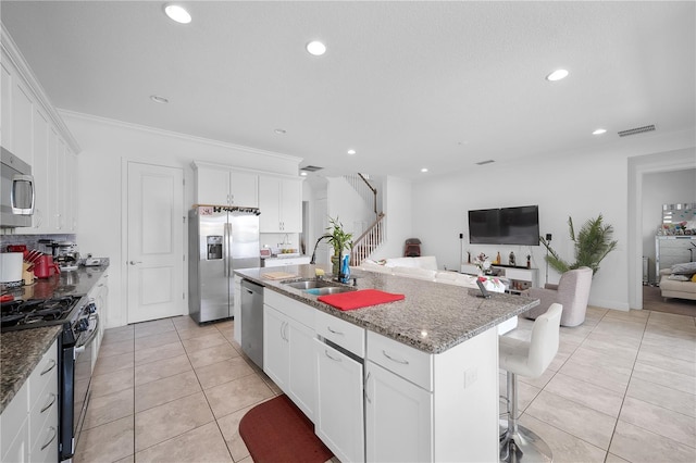 kitchen featuring appliances with stainless steel finishes, sink, a center island with sink, and white cabinets