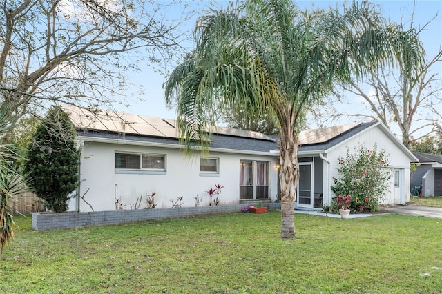 ranch-style house featuring a garage, a sunroom, a front lawn, and solar panels