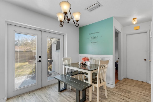 dining room featuring french doors, an inviting chandelier, and light hardwood / wood-style floors