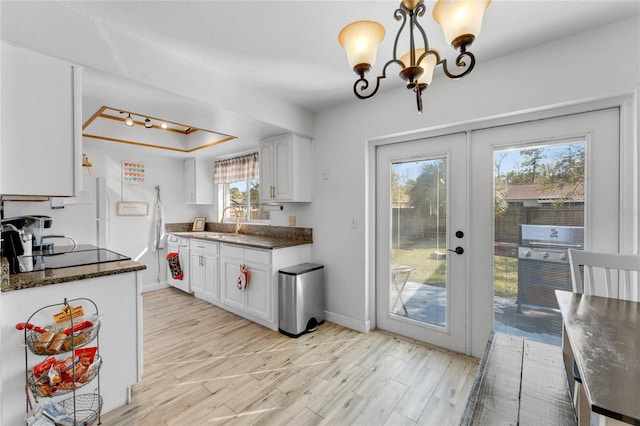 kitchen with sink, white cabinetry, light hardwood / wood-style flooring, a raised ceiling, and pendant lighting