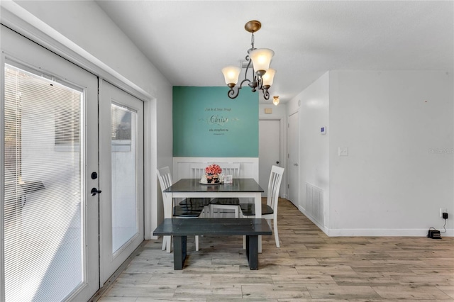 dining area featuring a notable chandelier, light hardwood / wood-style floors, and french doors