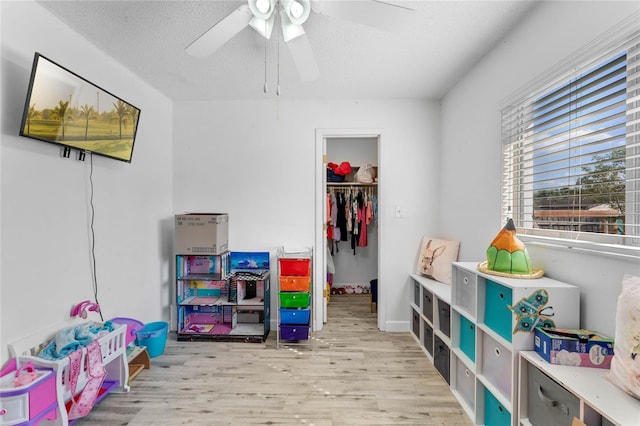 game room with ceiling fan, a textured ceiling, and light wood-type flooring