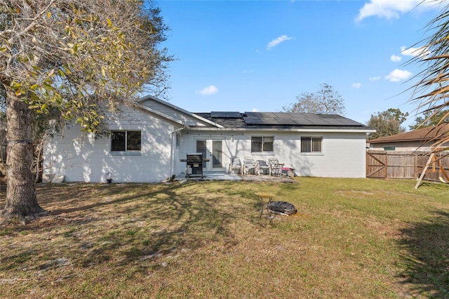 back of house with a fire pit, a lawn, a patio, and solar panels