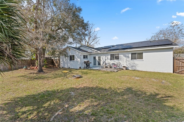 rear view of property featuring a yard, a patio, and solar panels