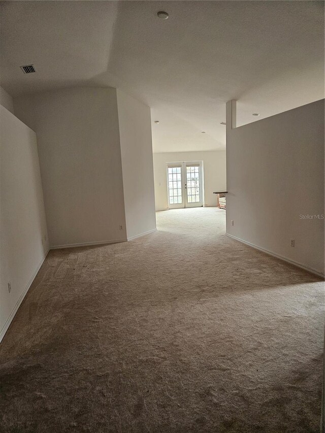 carpeted spare room featuring visible vents and baseboards