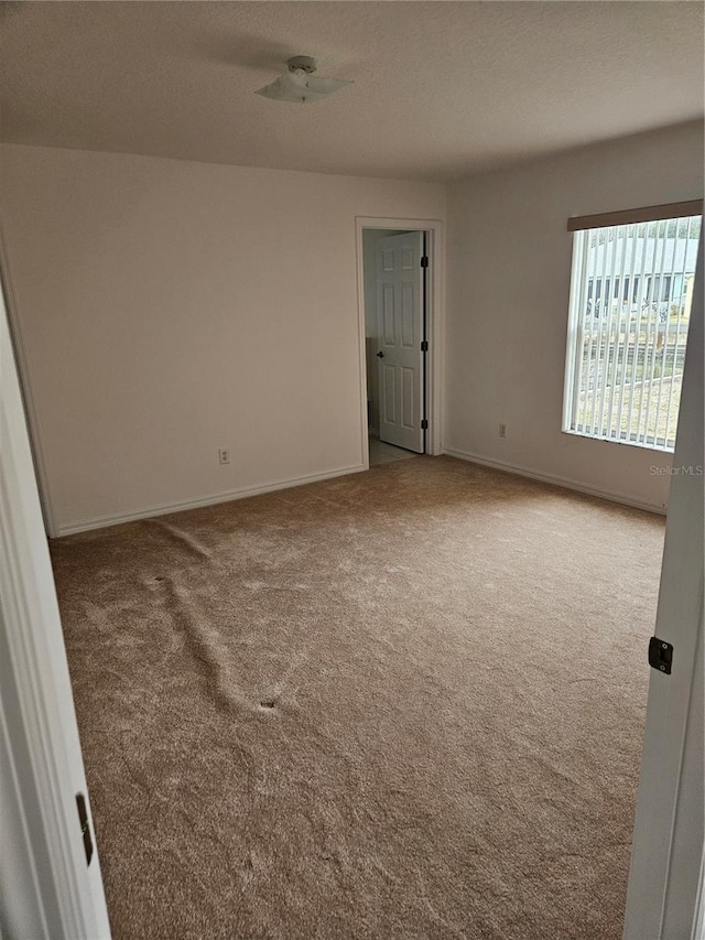 carpeted spare room with baseboards and a textured ceiling