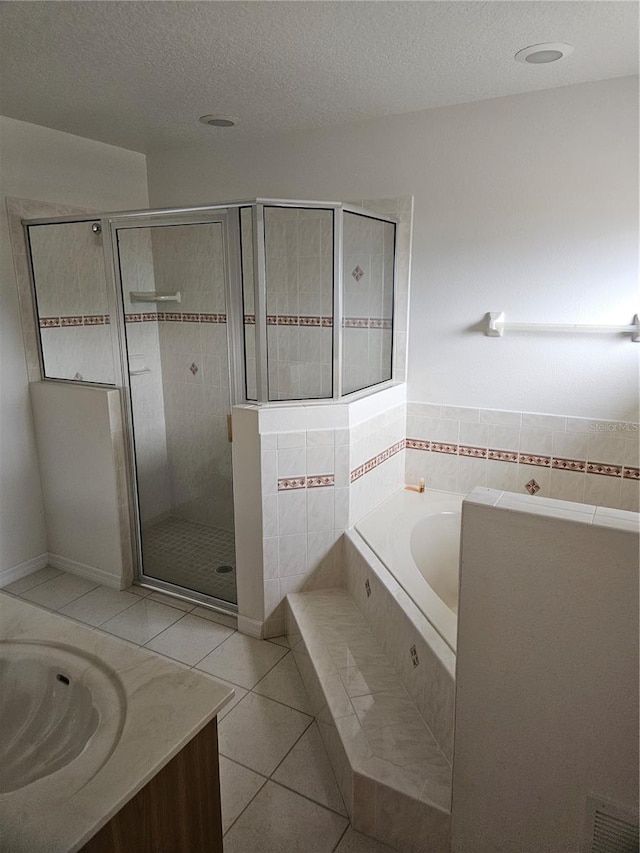 bathroom featuring a stall shower, a bath, tile patterned floors, a textured ceiling, and vanity