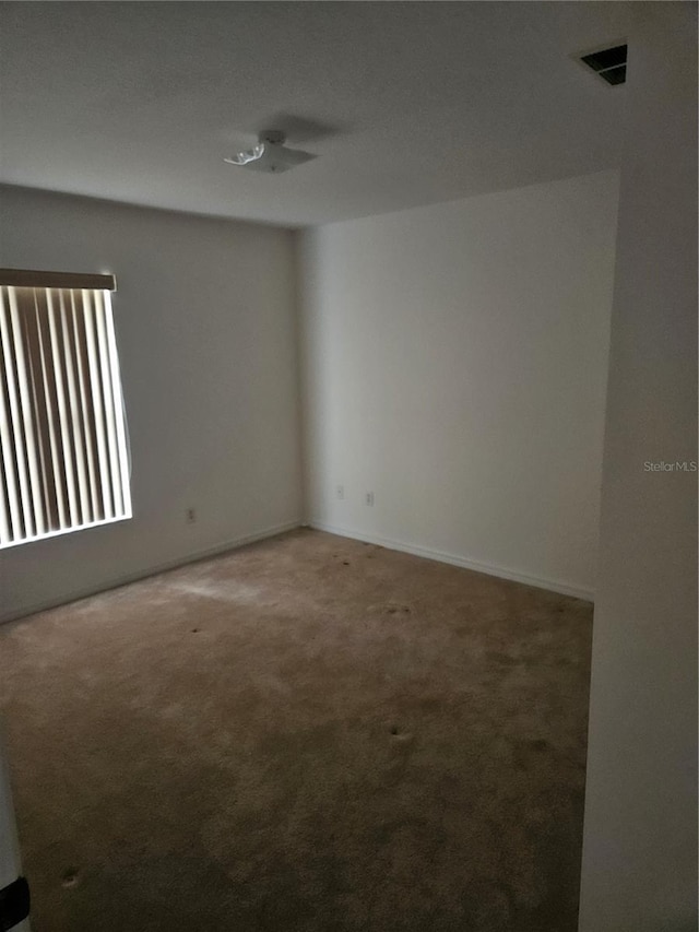 carpeted spare room featuring visible vents and baseboards