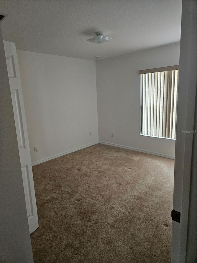 carpeted spare room with baseboards