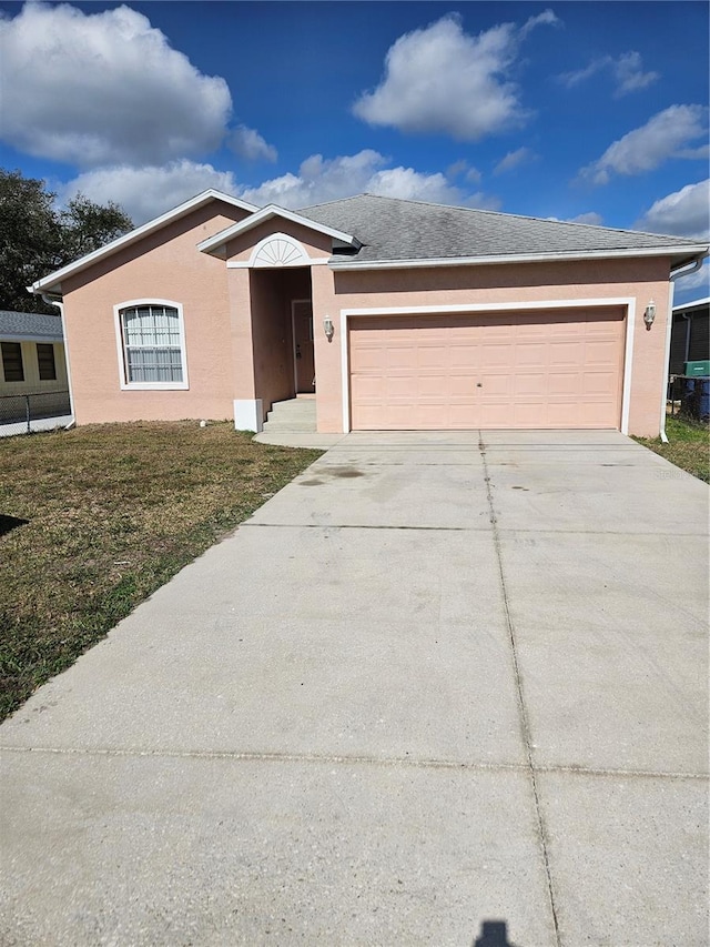 single story home with a garage, a front yard, driveway, and stucco siding