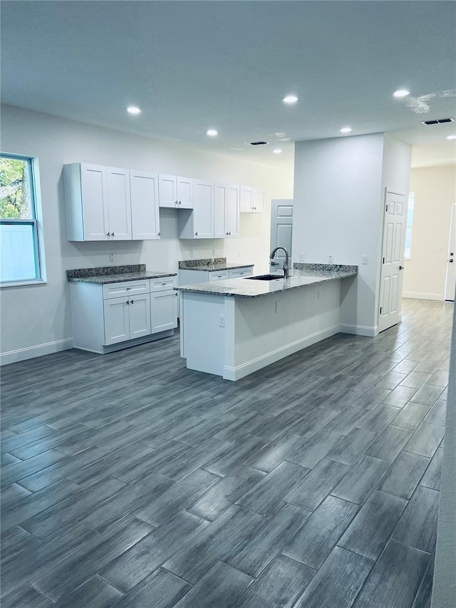 kitchen featuring dark wood finished floors, visible vents, a sink, and a peninsula