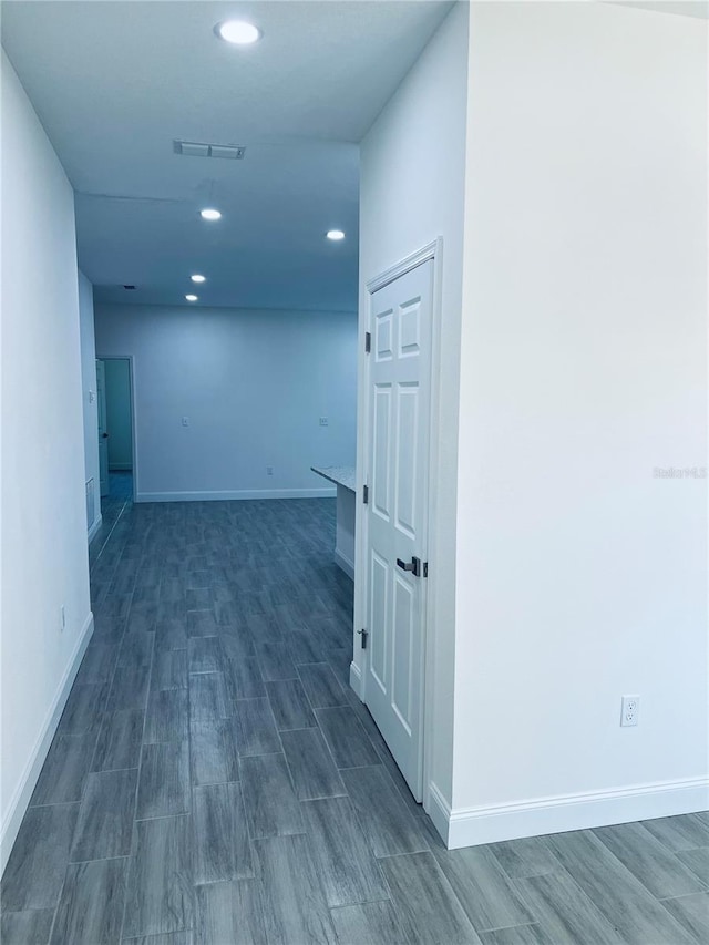 corridor with wood tiled floor, visible vents, baseboards, and recessed lighting