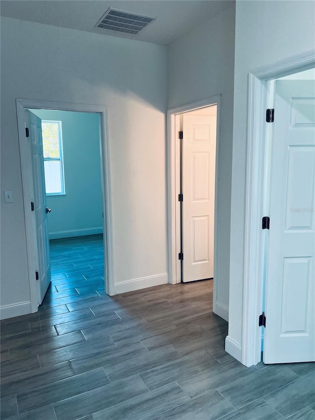 hallway featuring visible vents, baseboards, and wood finished floors