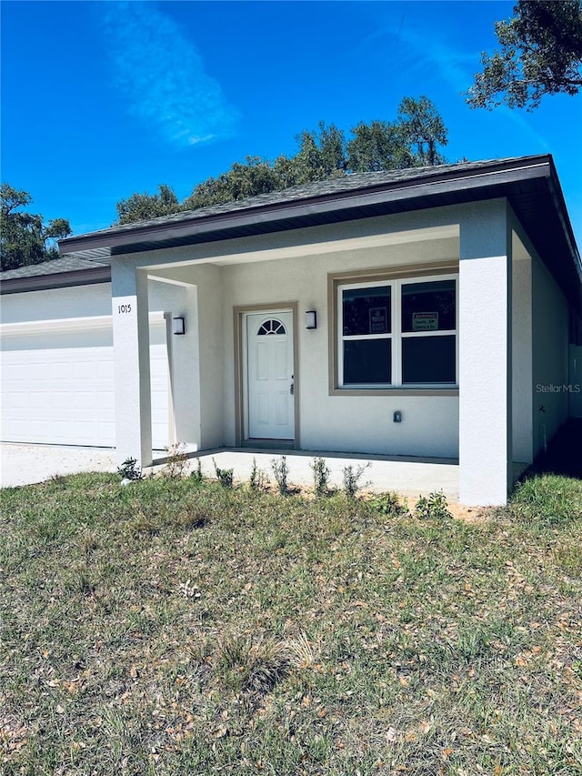 ranch-style home with an attached garage, a front yard, and stucco siding