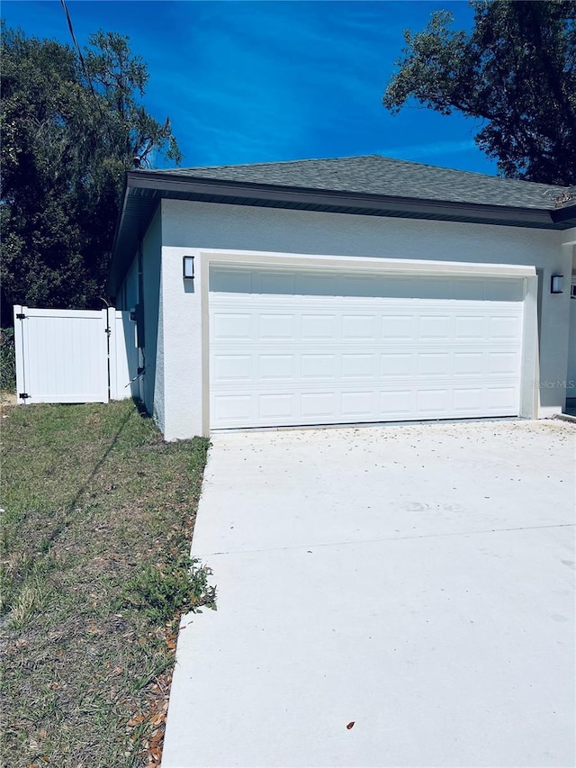 garage with concrete driveway and fence