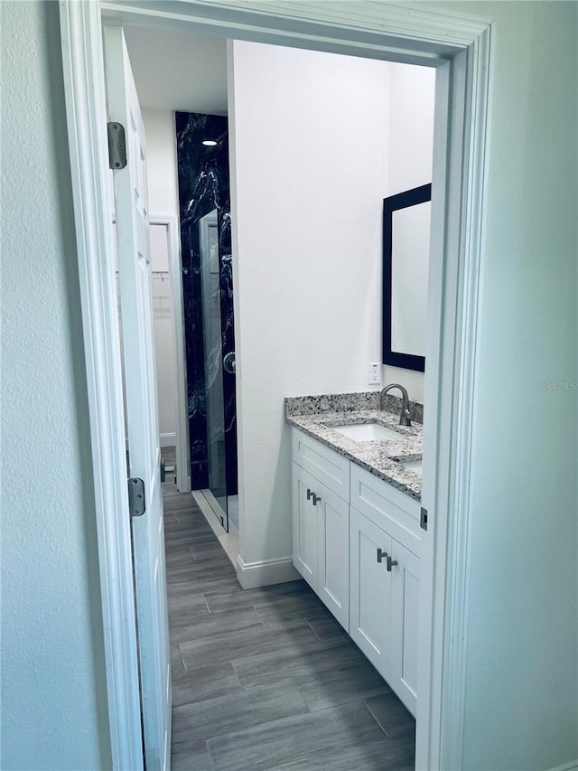 full bathroom with wood finish floors, vanity, and a shower stall