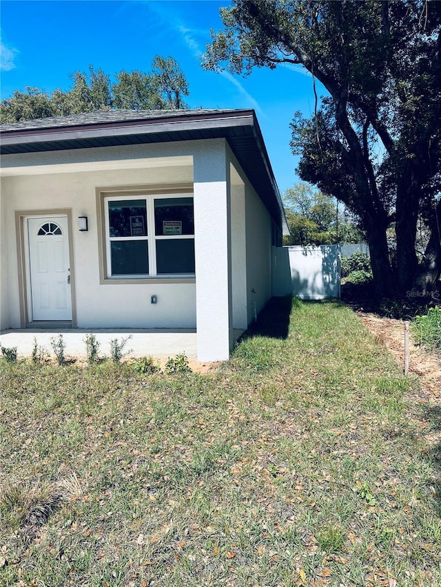 exterior space featuring a yard, fence, and stucco siding