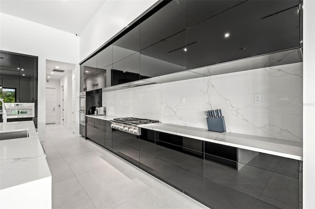 kitchen featuring appliances with stainless steel finishes, sink, light stone counters, and decorative backsplash