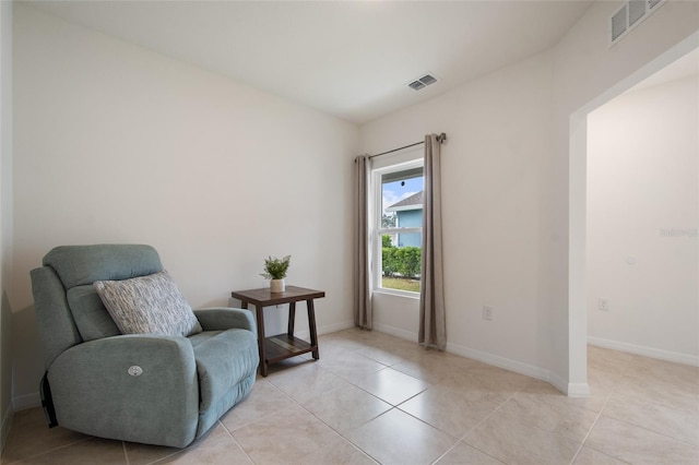 living area with light tile patterned flooring, visible vents, and baseboards