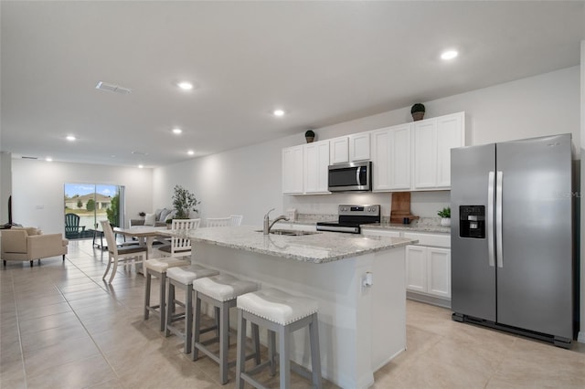 kitchen with a center island with sink, visible vents, a kitchen breakfast bar, stainless steel appliances, and a sink