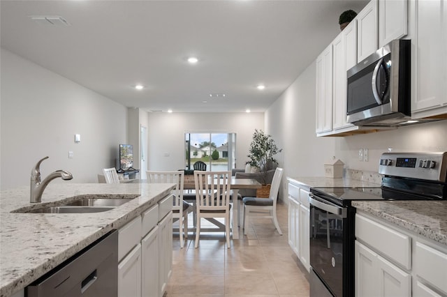 kitchen with visible vents, white cabinets, stainless steel appliances, a sink, and light tile patterned flooring