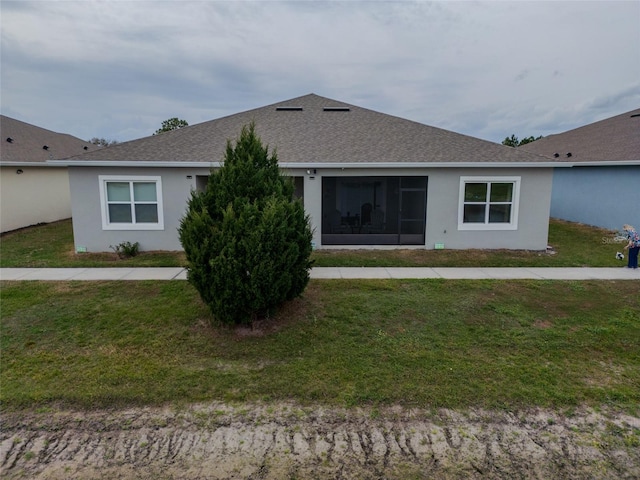 rear view of property with a shingled roof, a lawn, and stucco siding