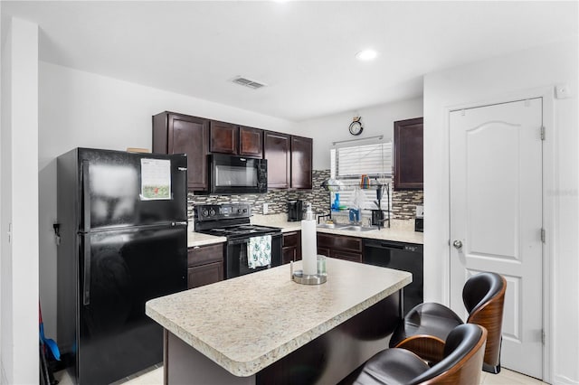 kitchen with sink, a breakfast bar area, a kitchen island, decorative backsplash, and black appliances