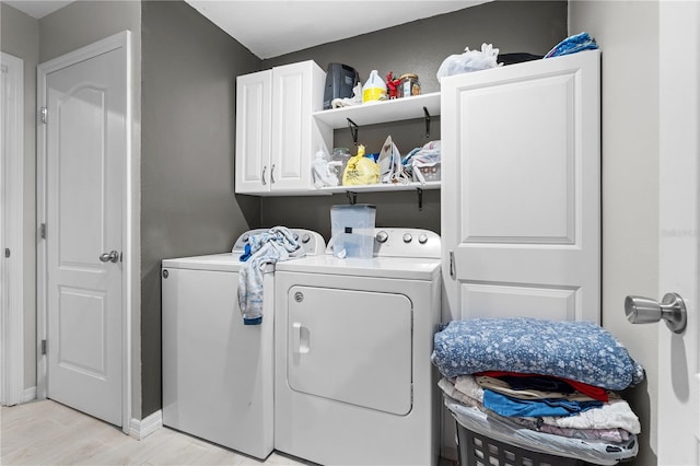 laundry area featuring cabinets, washing machine and clothes dryer, and light hardwood / wood-style floors