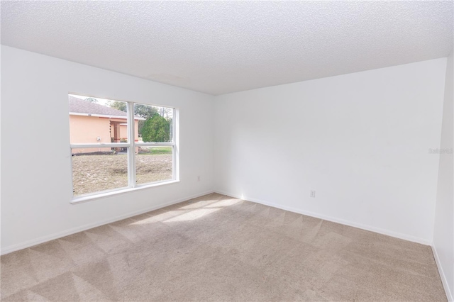 spare room featuring light carpet and a textured ceiling