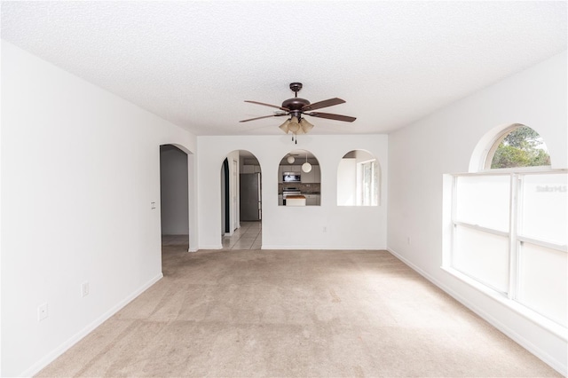 spare room featuring a textured ceiling, light colored carpet, and ceiling fan