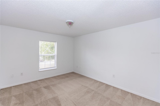 spare room featuring light carpet and a textured ceiling