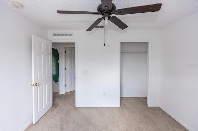 unfurnished bedroom with ceiling fan, light carpet, a textured ceiling, and a closet