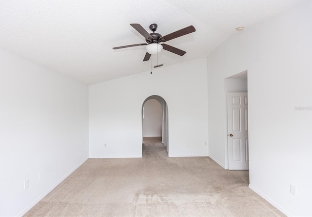 spare room featuring light carpet, a textured ceiling, vaulted ceiling, and ceiling fan