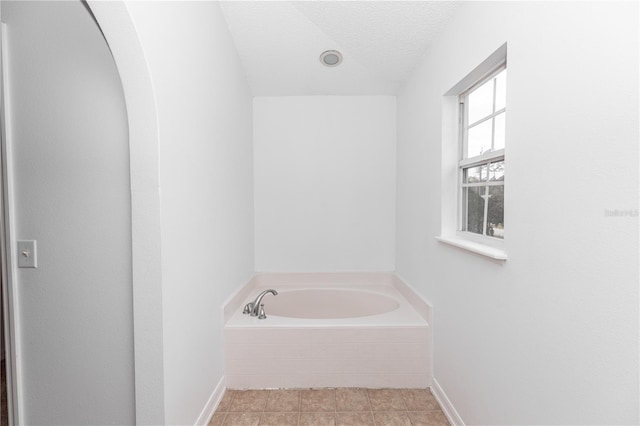 bathroom with a textured ceiling, tile patterned floors, and a bathing tub