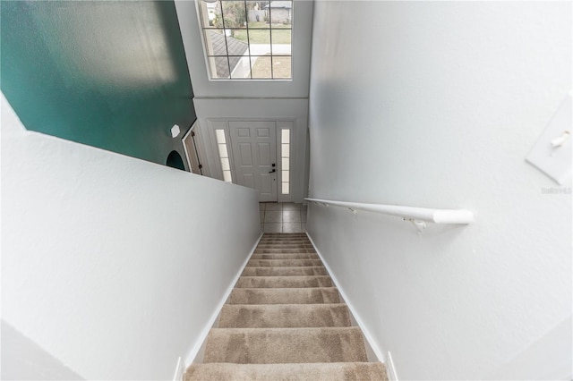 stairs with carpet flooring and a high ceiling