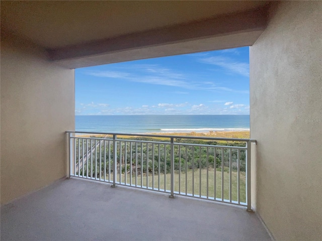 balcony with a water view and a view of the beach