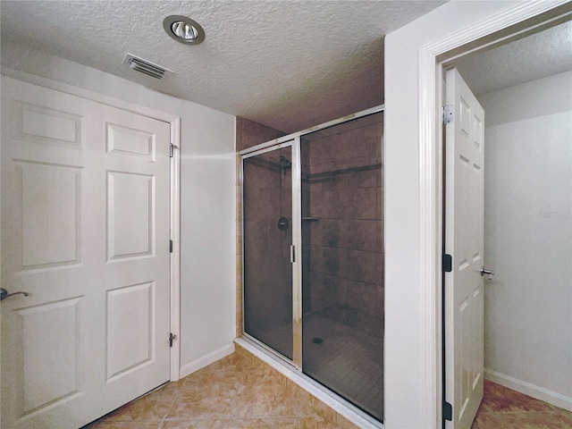 bathroom featuring a shower with shower door and a textured ceiling