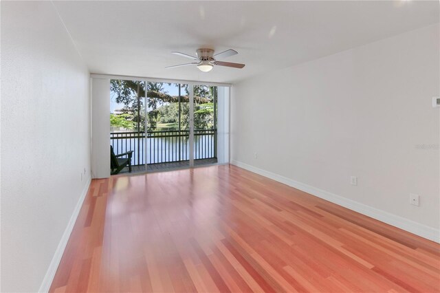 empty room with hardwood / wood-style floors, floor to ceiling windows, and ceiling fan