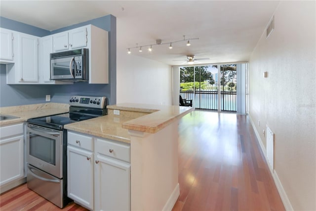 kitchen with stainless steel appliances, white cabinetry, light wood-type flooring, and kitchen peninsula