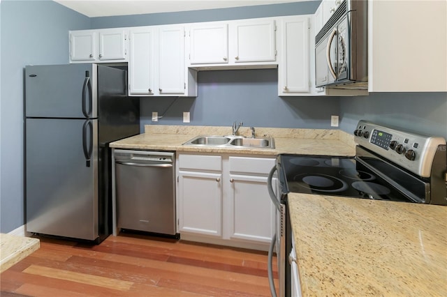 kitchen featuring appliances with stainless steel finishes, sink, white cabinets, and light hardwood / wood-style flooring