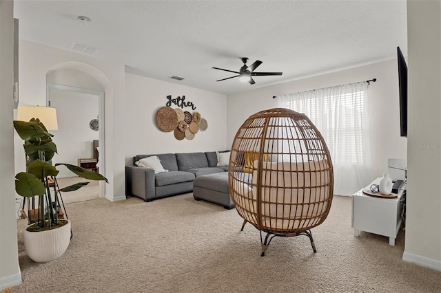 carpeted living room with a textured ceiling and ceiling fan